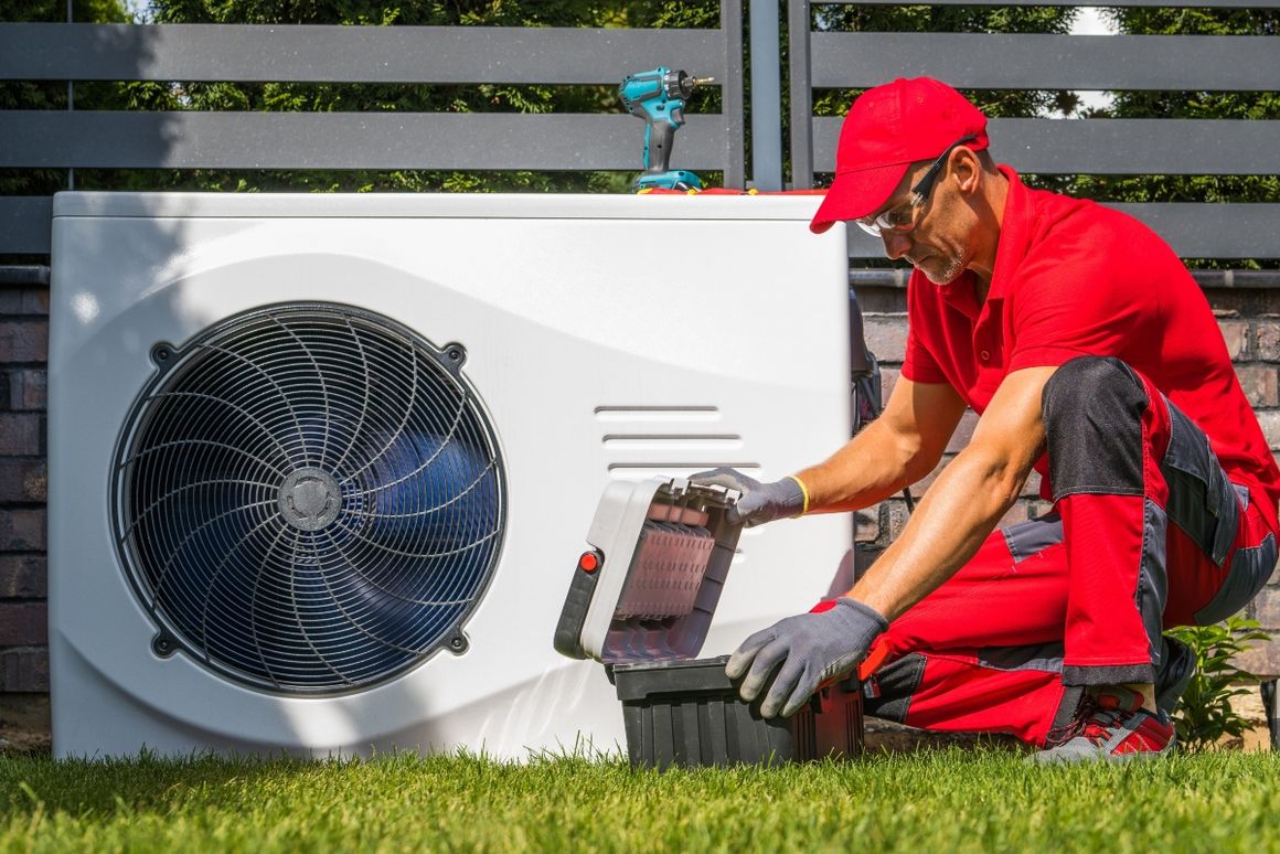 Person mit Werkzeugkoffer vor Wärmepumpe